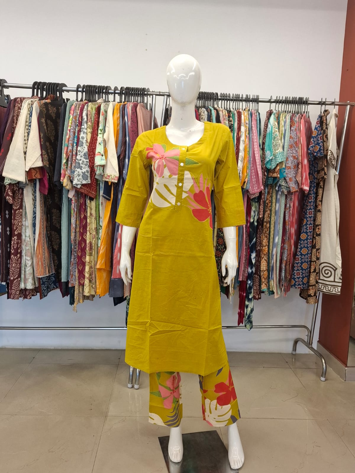 Mannequin wearing a yellow dress with floral patterns in a clothing store.
