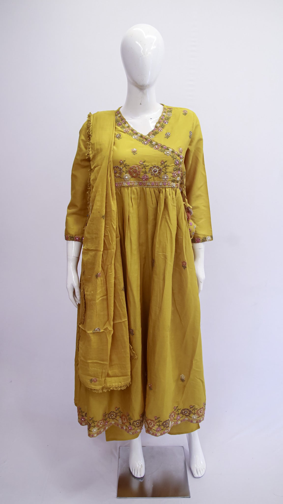 Yellow embroidered dress on a mannequin against a white background