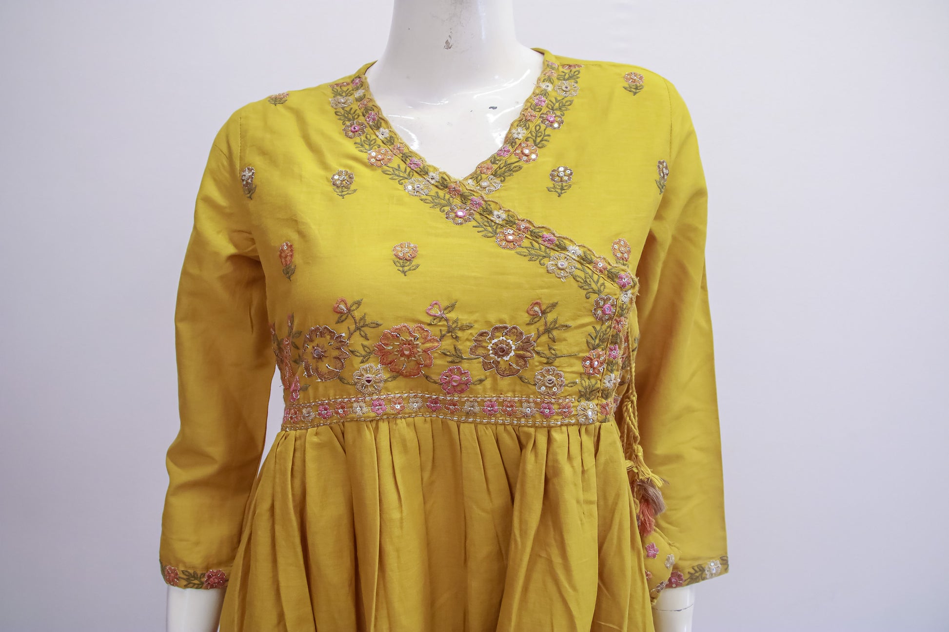 Yellow embroidered dress on a mannequin against a white background