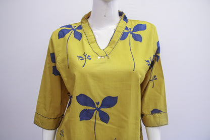 Yellow top with blue floral patterns on a mannequin against a white background