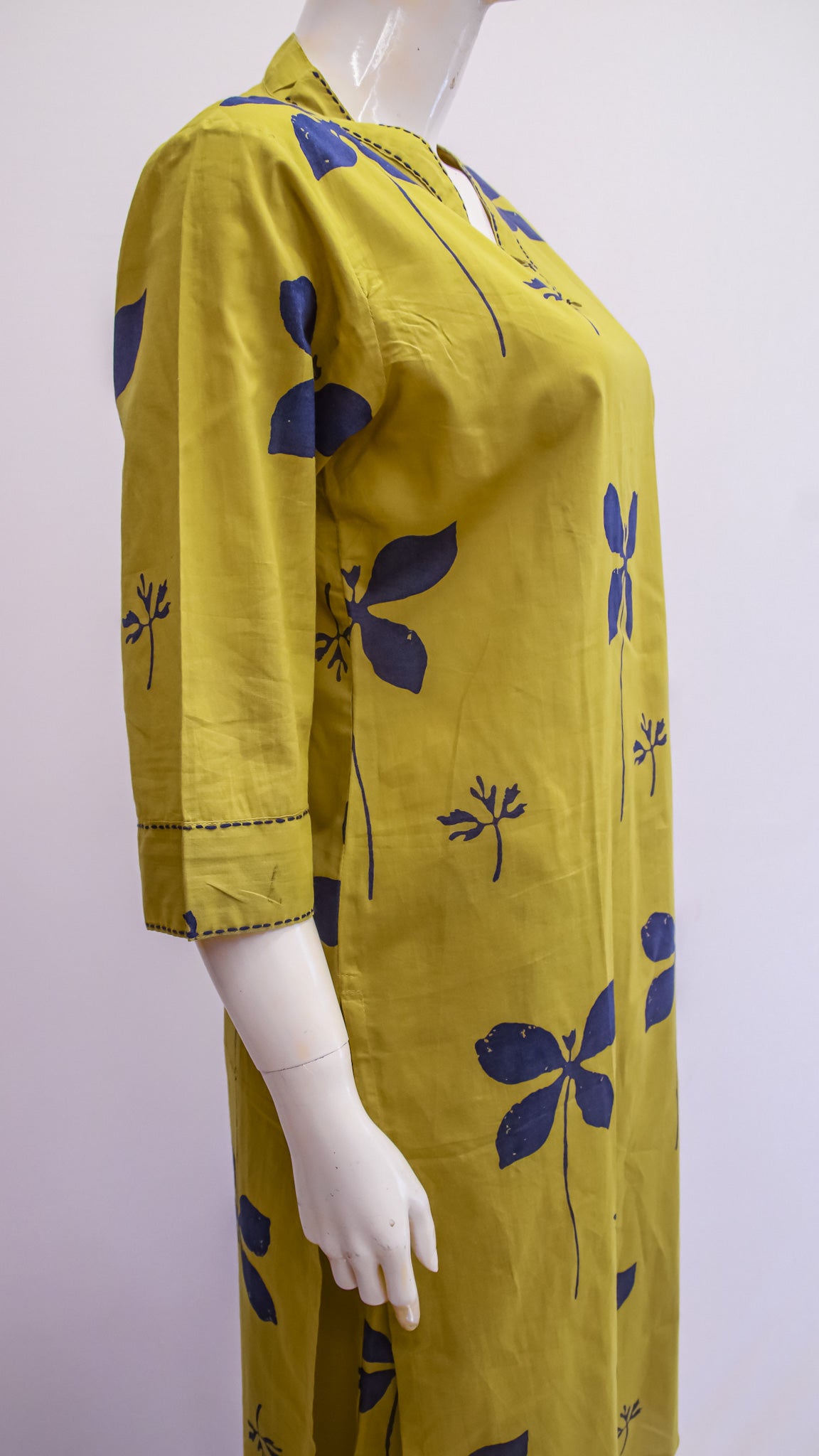 Yellow dress with blue floral patterns on a mannequin against a white background