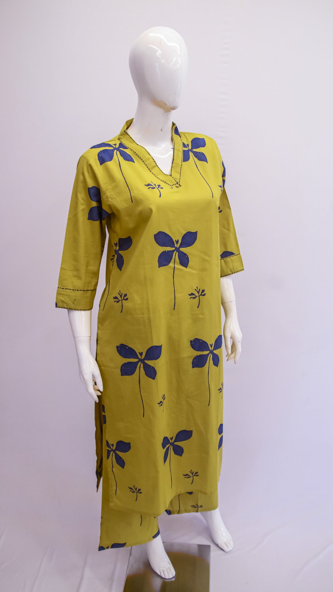 Yellow dress with blue floral patterns on a mannequin against a white background