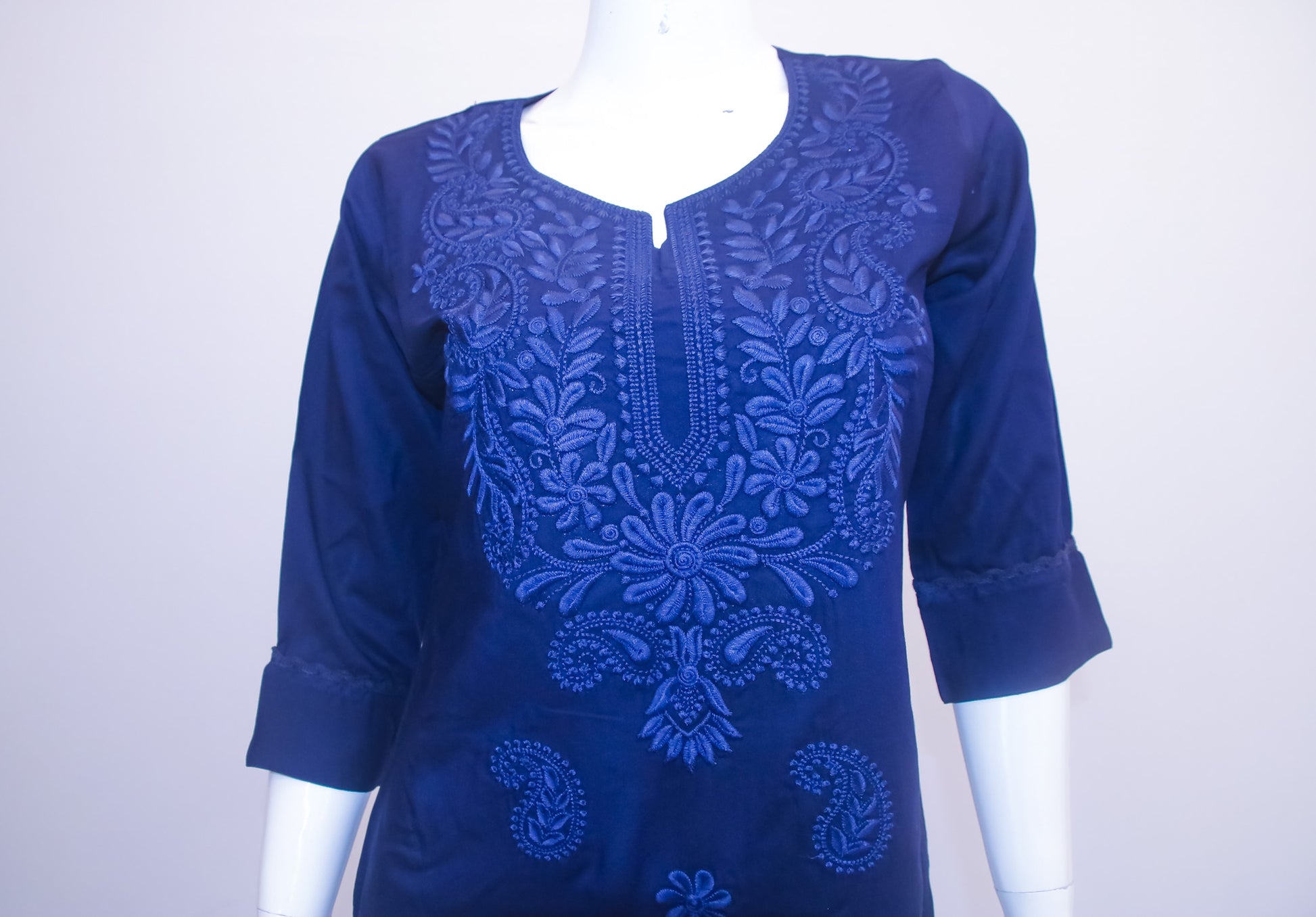 Blue embroidered top on a mannequin against a white background