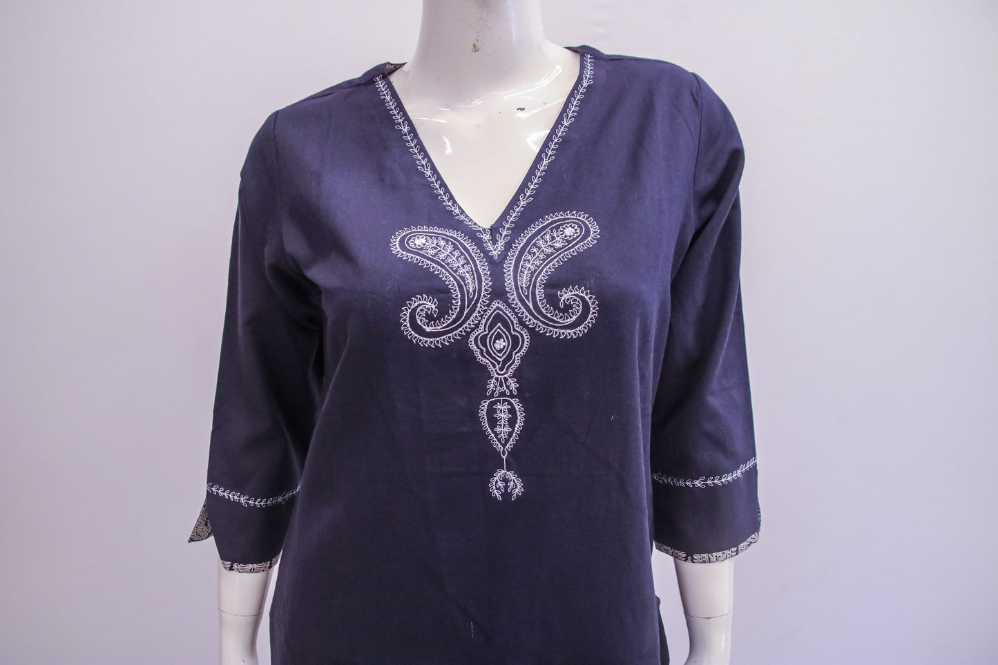Navy blue blouse with white embroidery on a mannequin against a white background