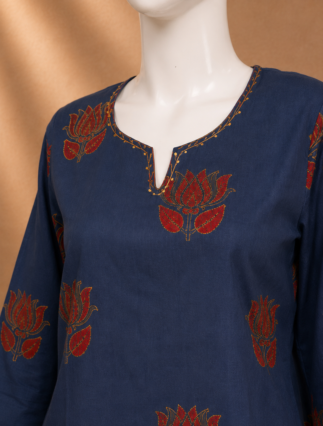 A navy blue cotton kurta with red and gold lotus flower embroidery, displayed on a white mannequin torso against a warm beige background.