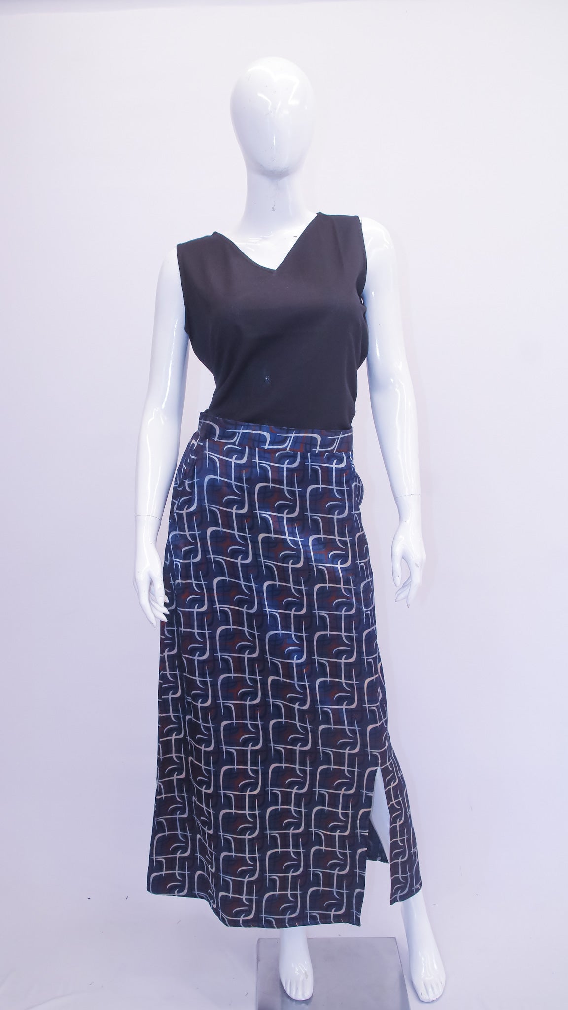 Mannequin wearing a black sleeveless top and patterned skirt on a white background