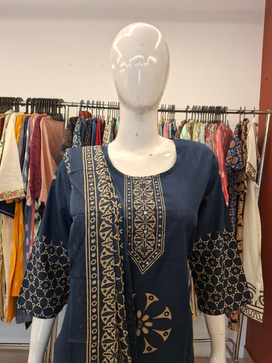 Navy blue dress with gold patterns on a mannequin against a clothing store background.