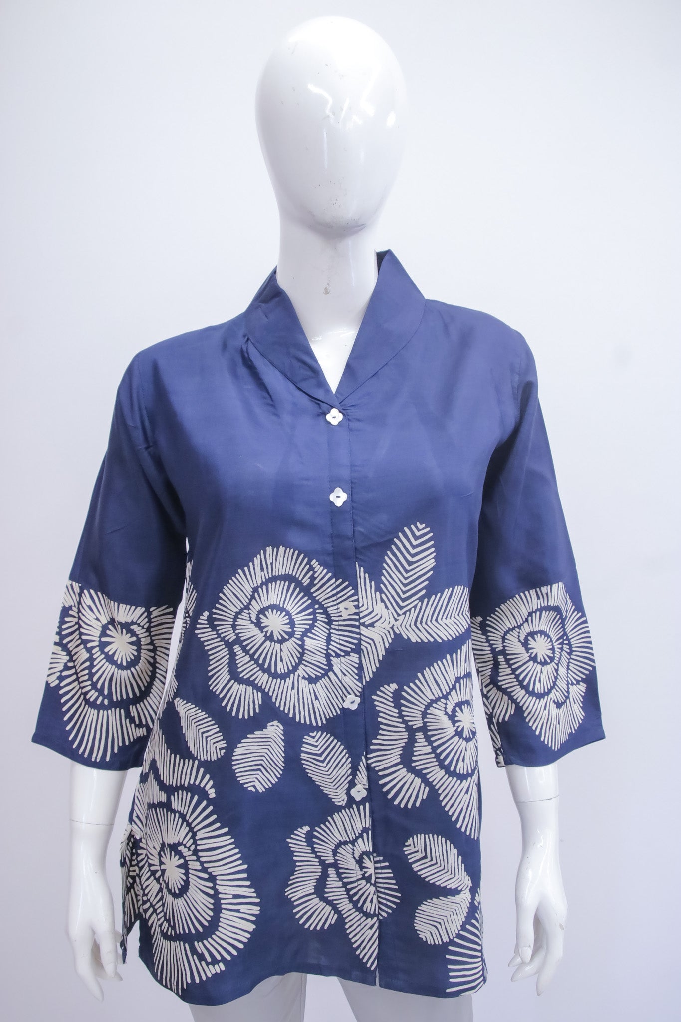 Blue blouse with white floral patterns on a mannequin against a white background