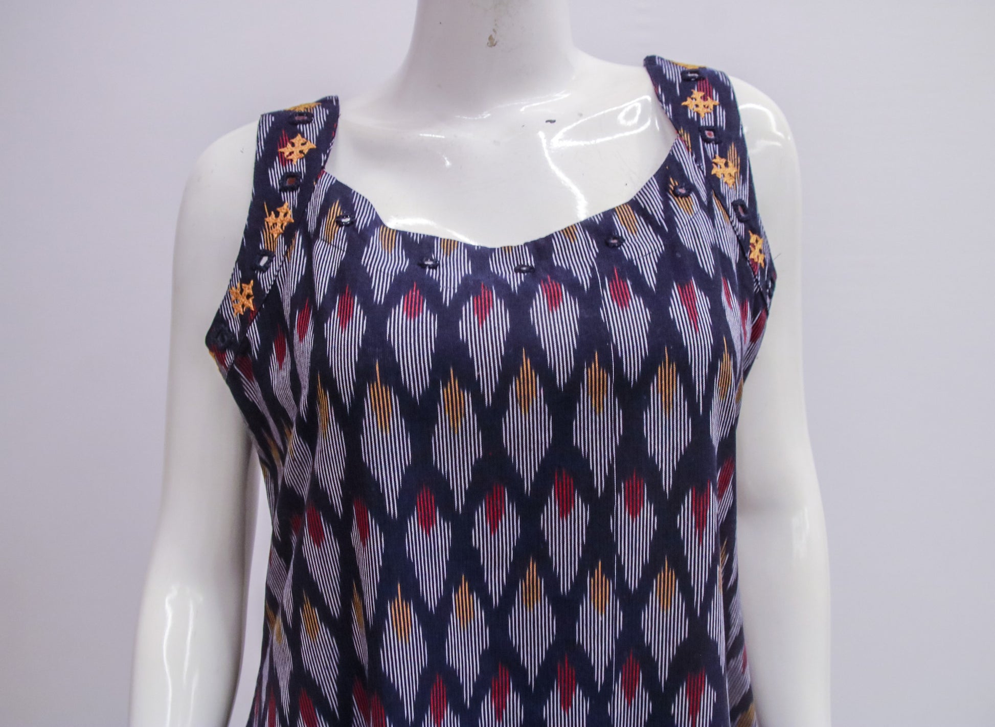Mannequin wearing a sleeveless top with a geometric pattern on a white background