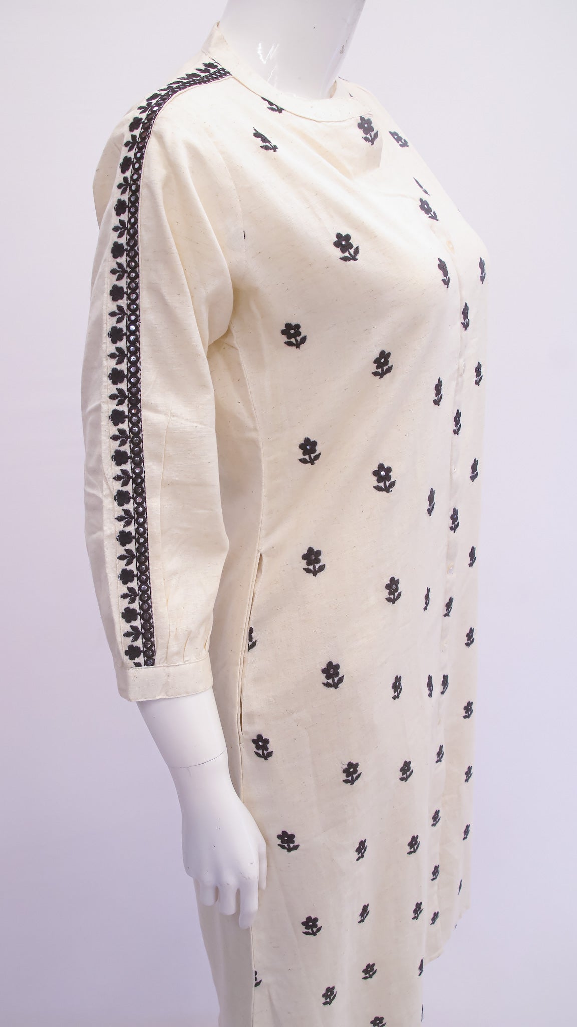 White dress with black floral patterns on a mannequin against a white background
