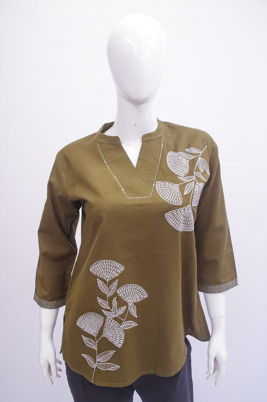 Green blouse with white floral embroidery on a mannequin against a white background