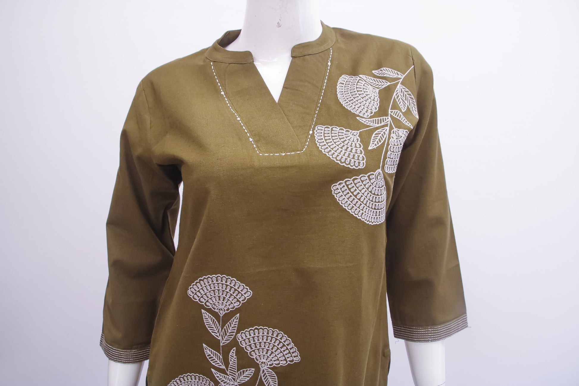 Brown top with white floral embroidery on a mannequin against a white background
