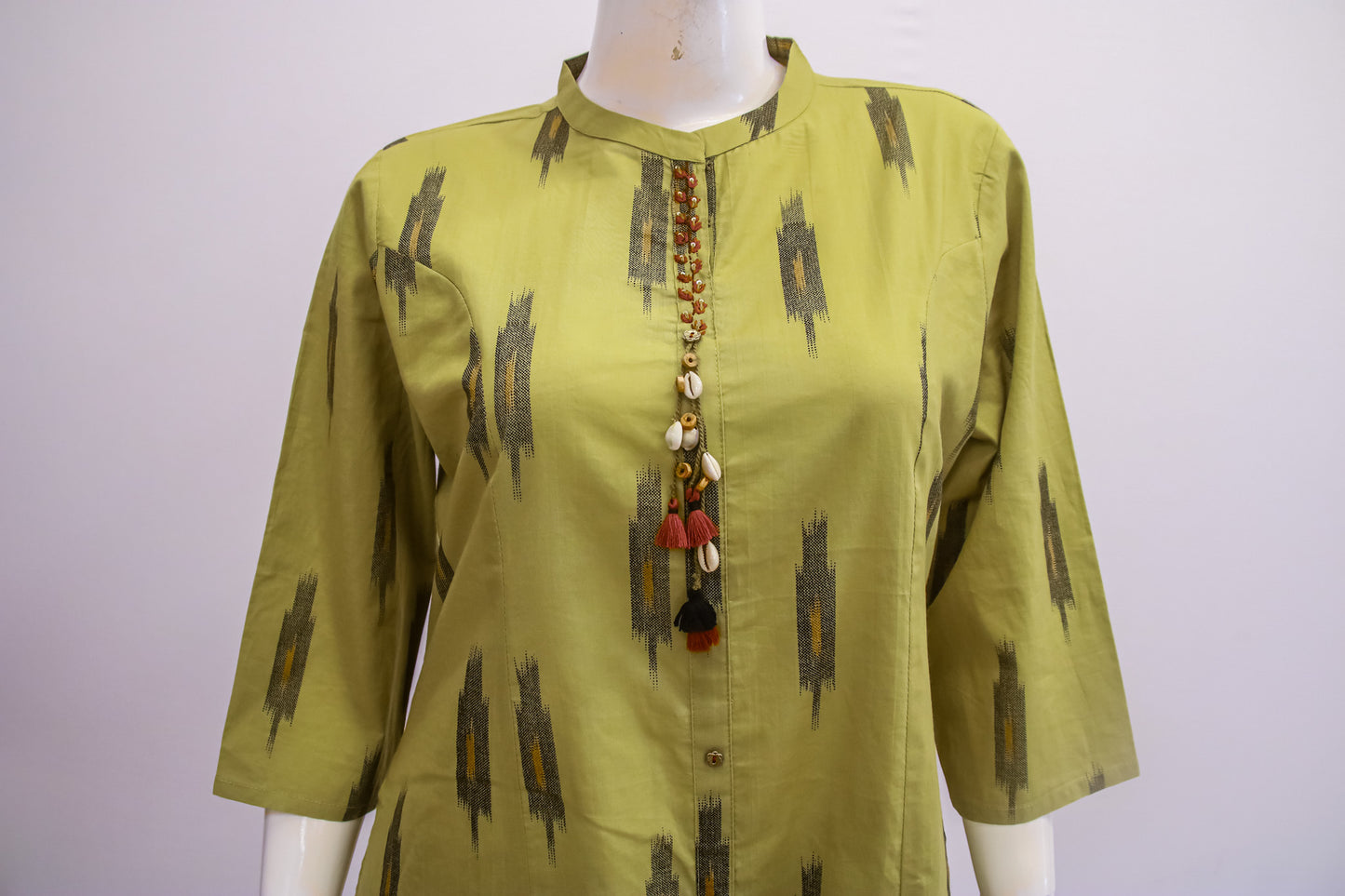 Green patterned blouse on a mannequin with a white background