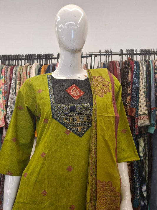 Green embroidered kurta on a mannequin with a colorful background of clothes.