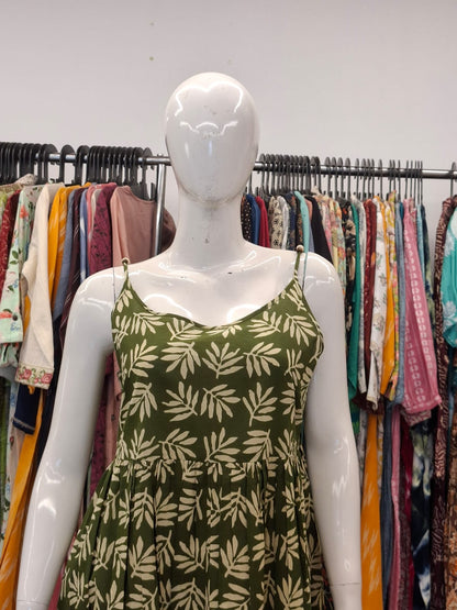 Mannequin wearing a green dress with leaf pattern in a clothing store setting.