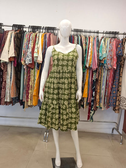 Mannequin wearing a green dress with leaf pattern in a clothing store setting.