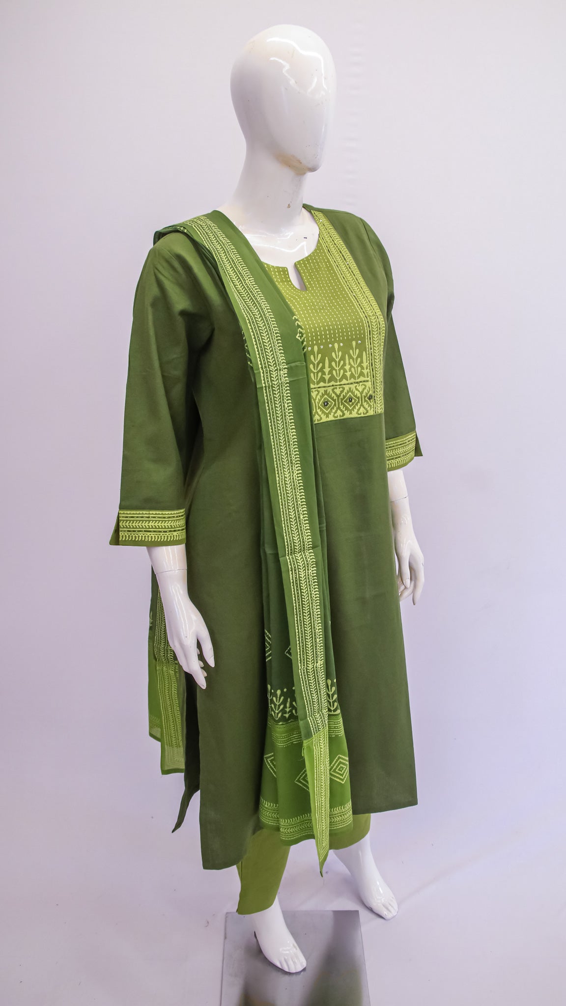 Green embroidered dress on a mannequin against a white background