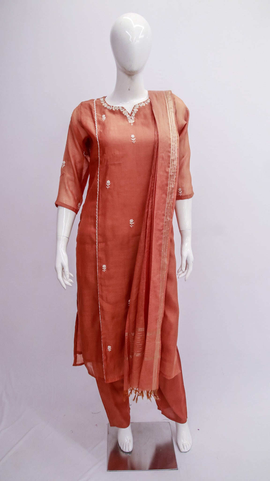 Mannequin wearing a rust-colored traditional outfit with a dupatta on a white background