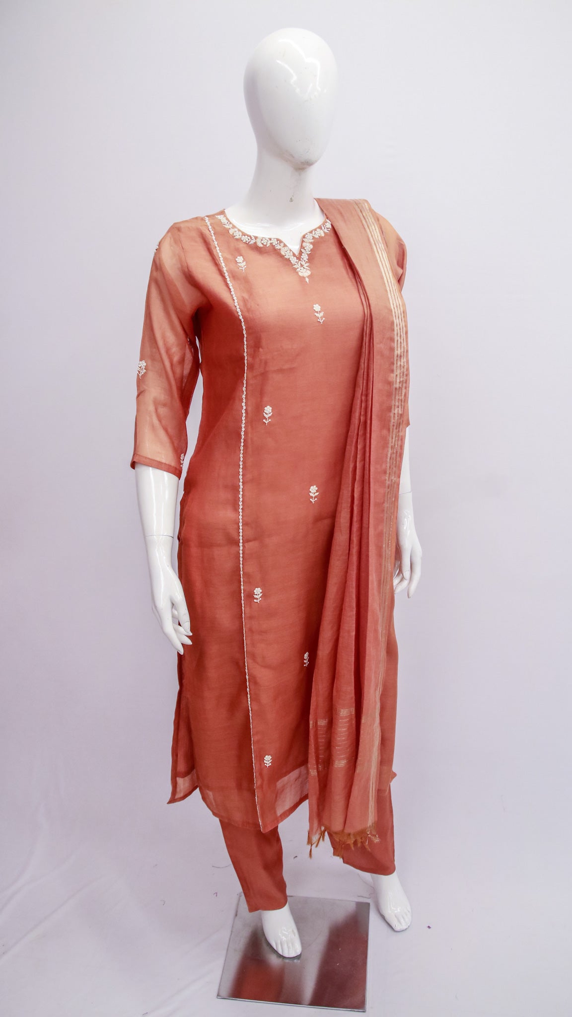 Mannequin wearing a rust-colored traditional outfit with a dupatta on a white background