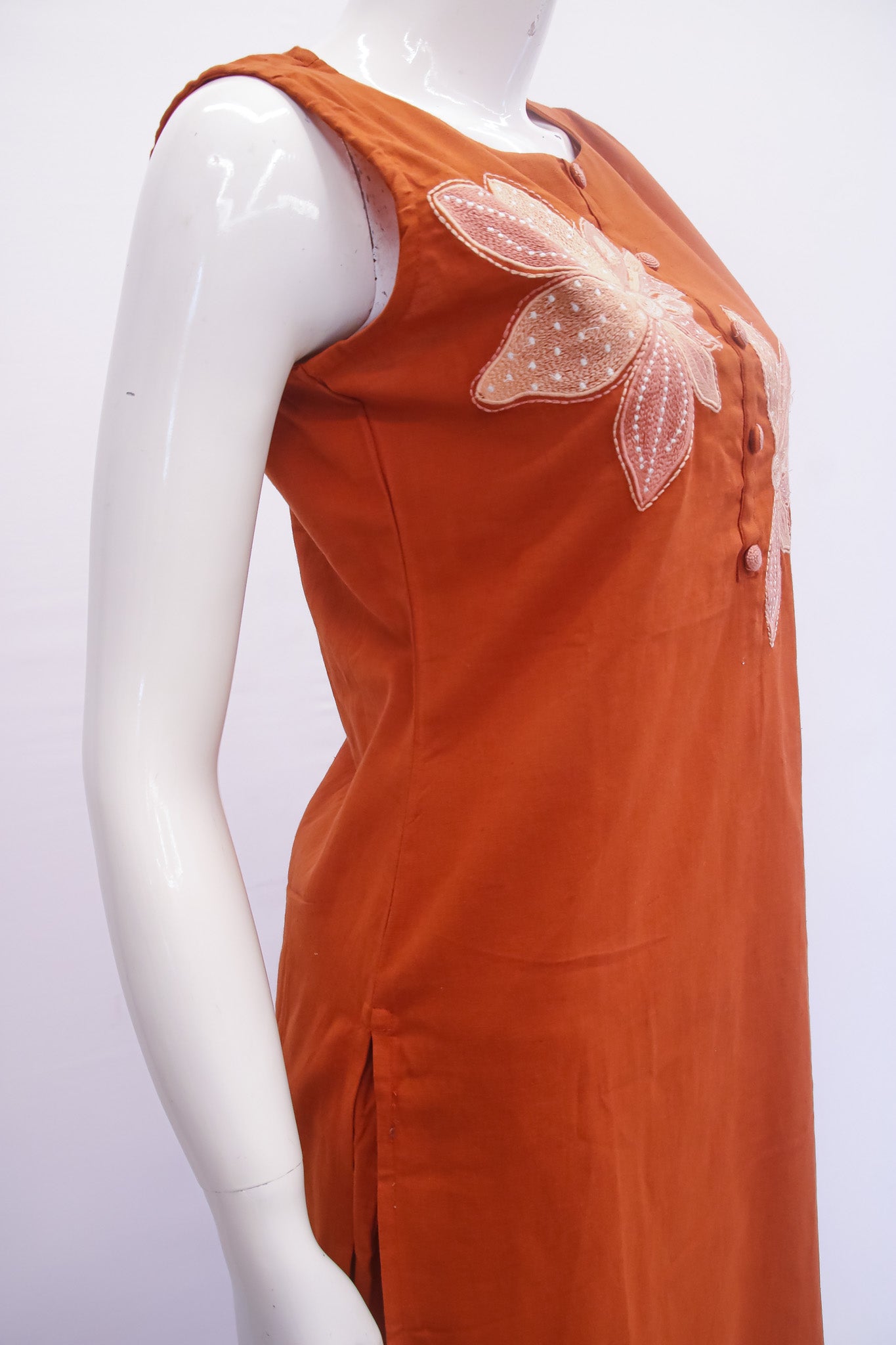 Orange dress with floral embroidery on a mannequin against a white background