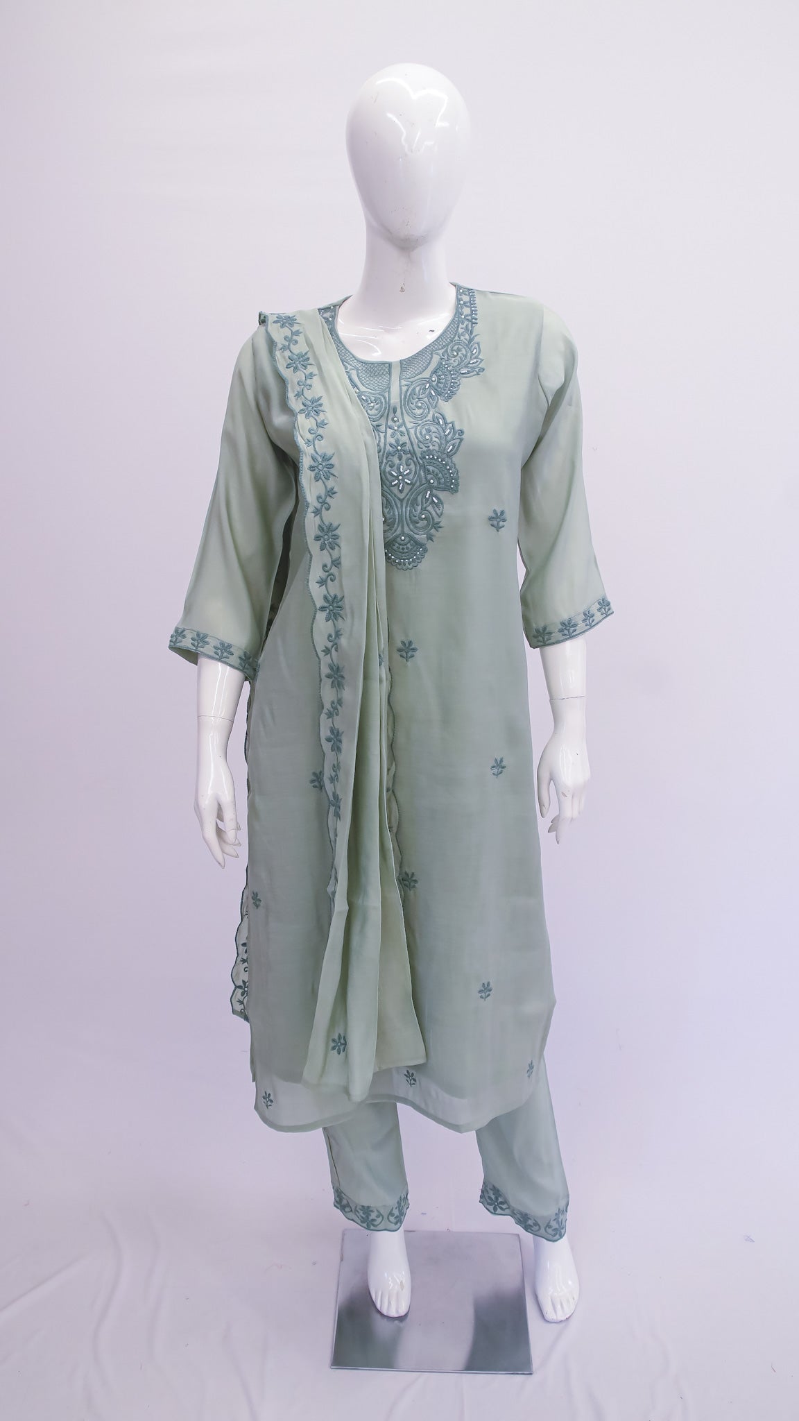 Green embroidered outfit on a mannequin against a white background