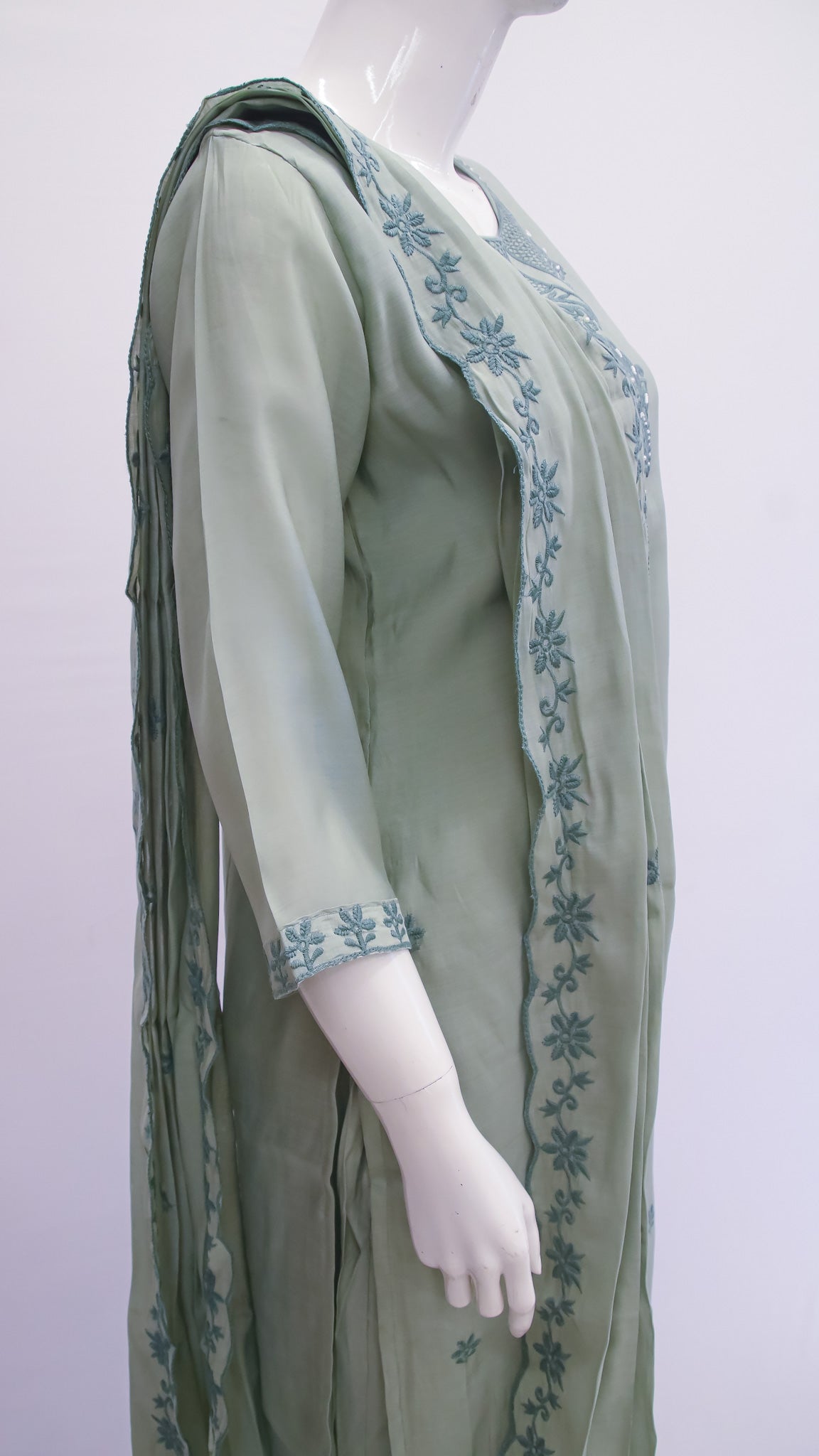 Mannequin wearing a green dress with floral embroidery on a white background
