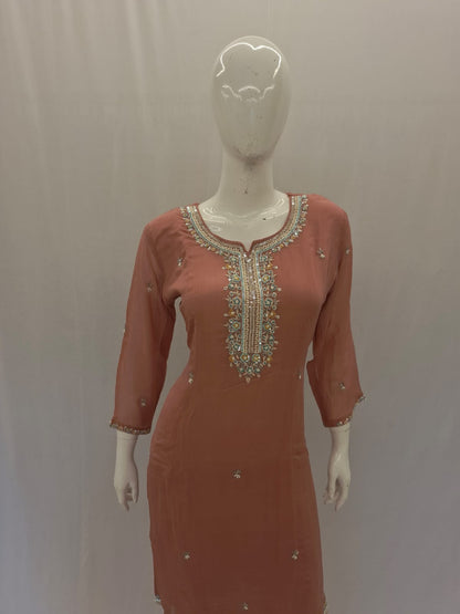 Coral dress with intricate beadwork on a mannequin against a plain background