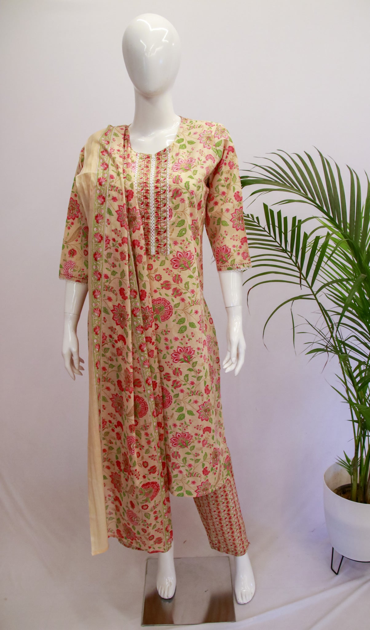 A mannequin displaying a peach colored cotton dupatta set with floral prints, consisting of a kurta, pant, and dupatta.