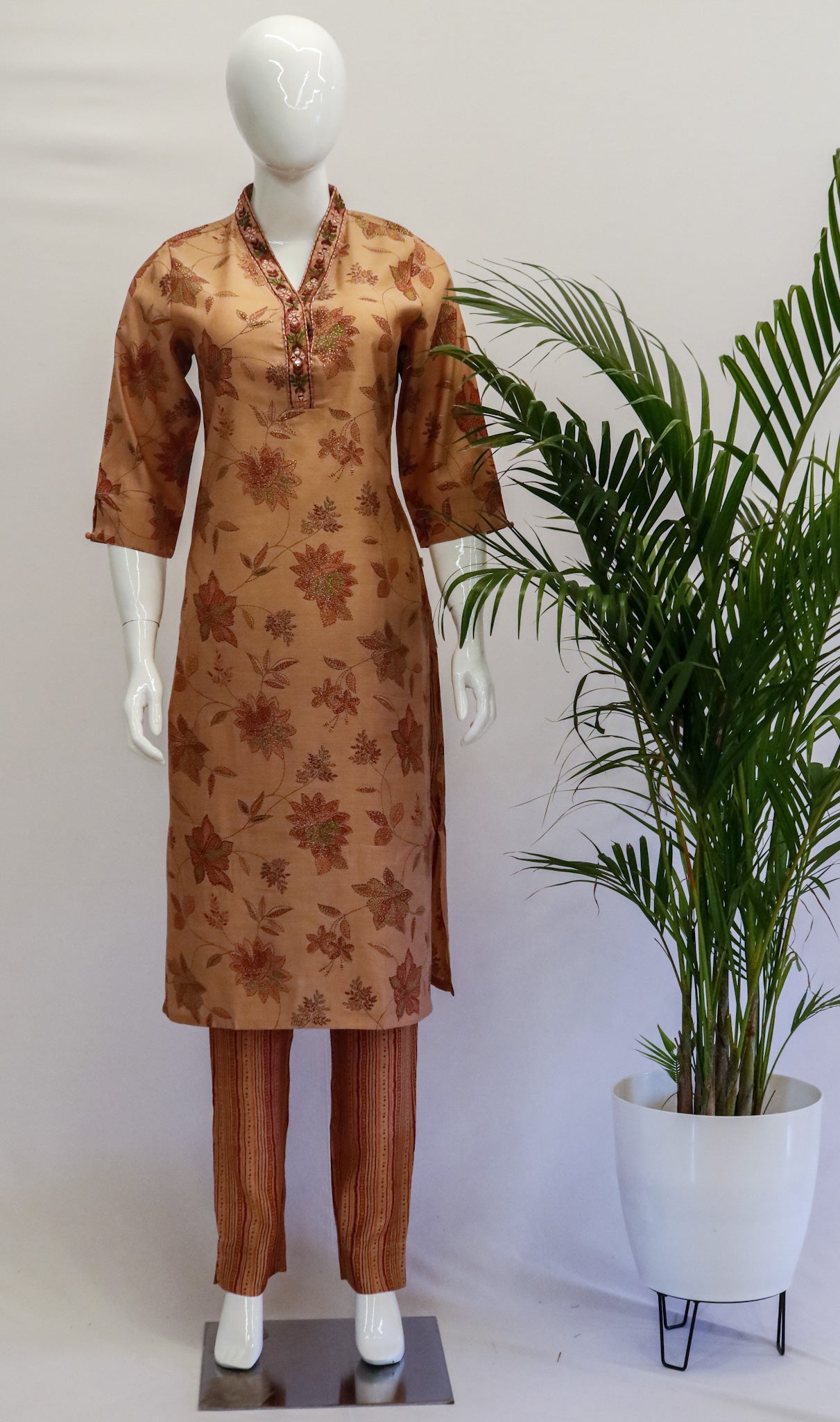 A mannequin wearing a peach-colored floral muslin top and pants with a V-neck and 3/4th sleeves.