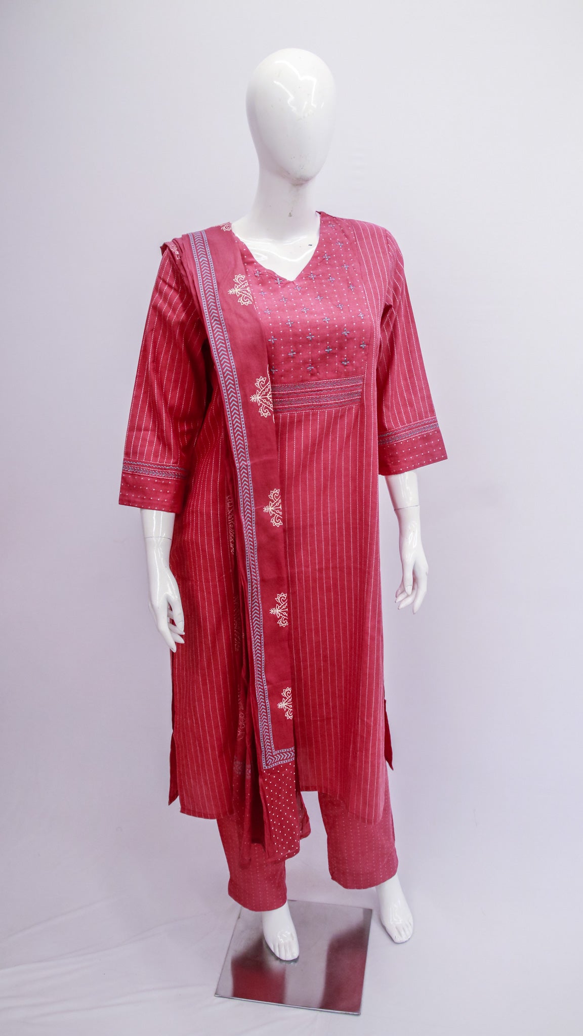 Red traditional outfit with white embroidery on a mannequin against a light gray background