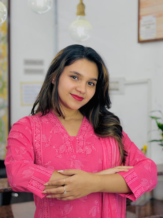 Woman wearing a pink traditional outfit in a home setting