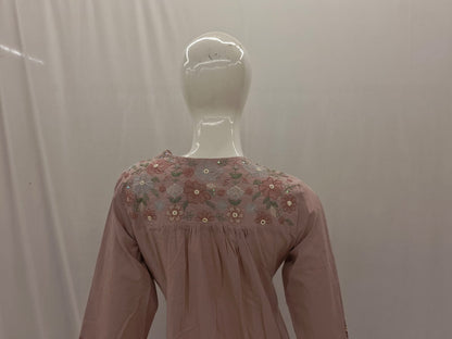 Mannequin wearing a pink blouse with floral embroidery on a plain background