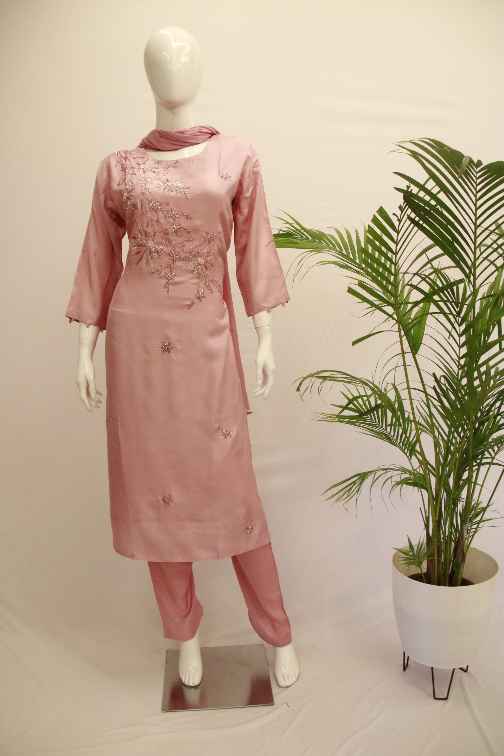 A mannequin displaying a pink silk dupatta set with embroidered details, consisting of a kurta, pants, and a dupatta.