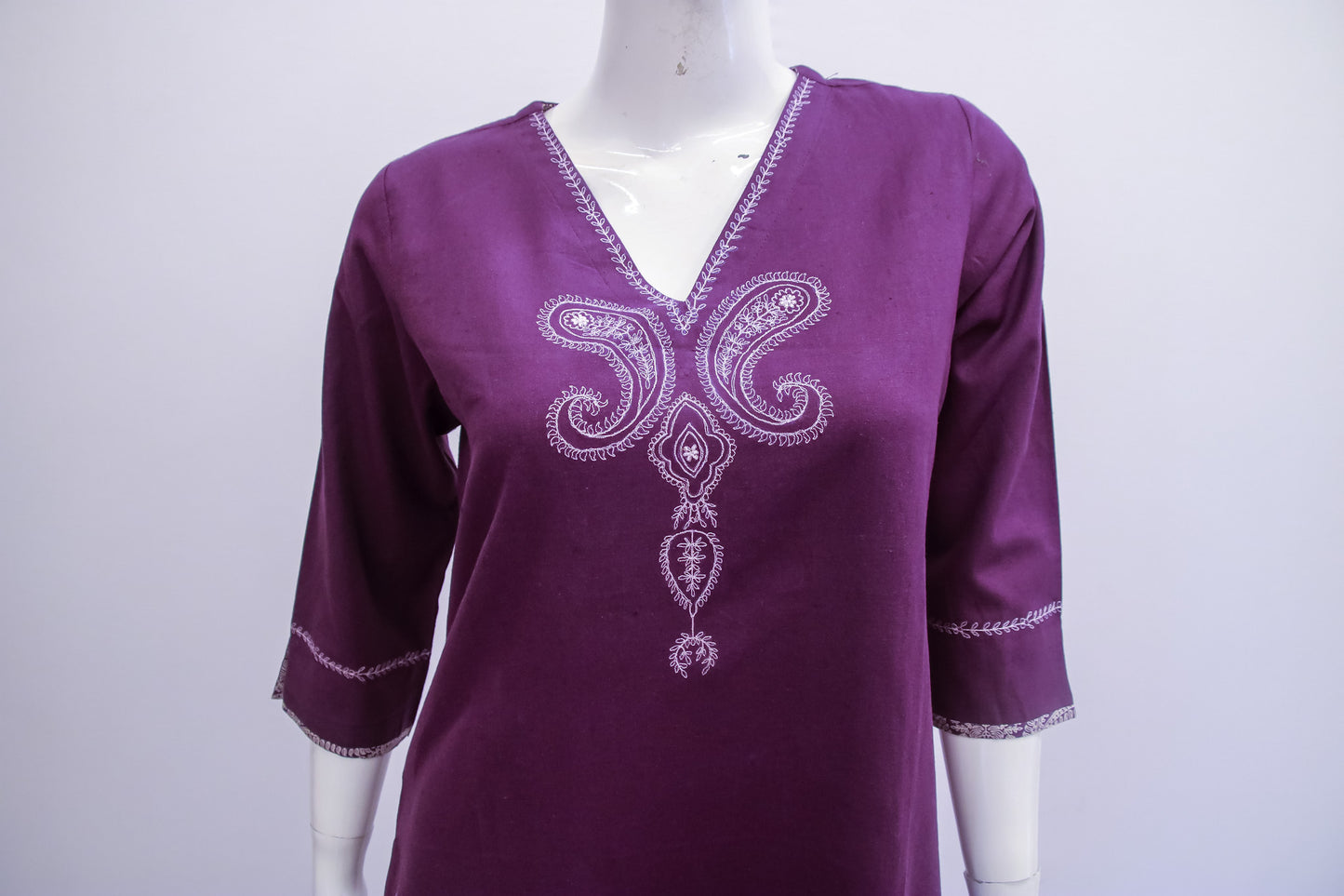 Purple embroidered dress on a mannequin against a white background