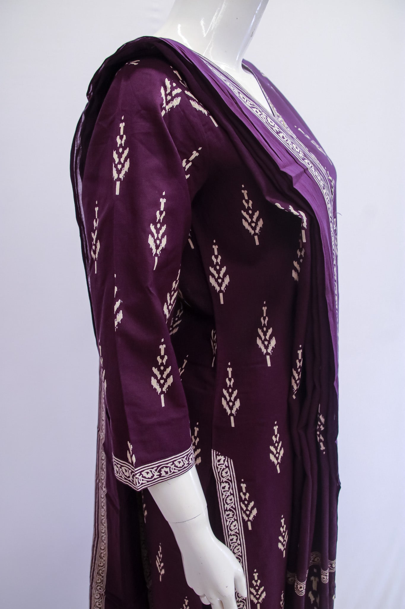 Purple traditional outfit with intricate patterns on a mannequin against a white background