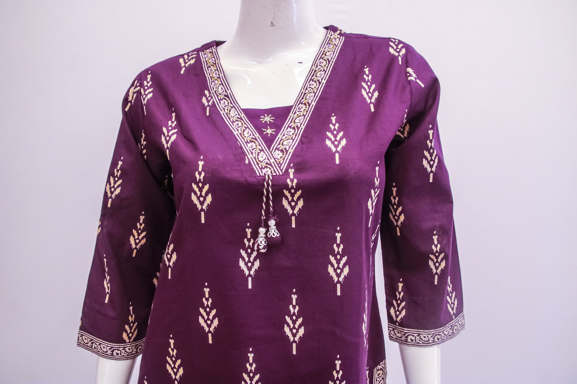 Purple traditional top with white patterns on a mannequin against a white background