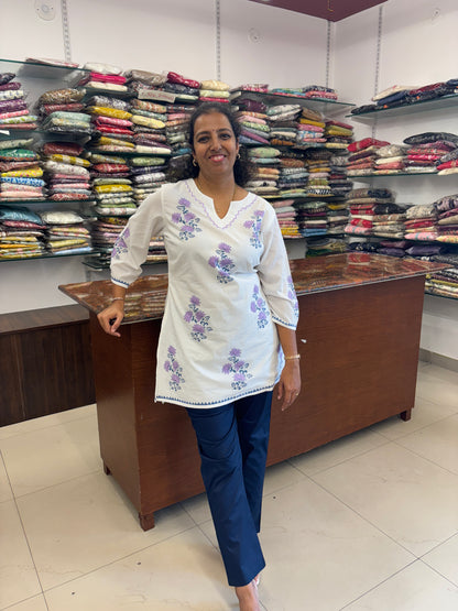 Woman standing in a fabric store with shelves of colorful fabric behind her.