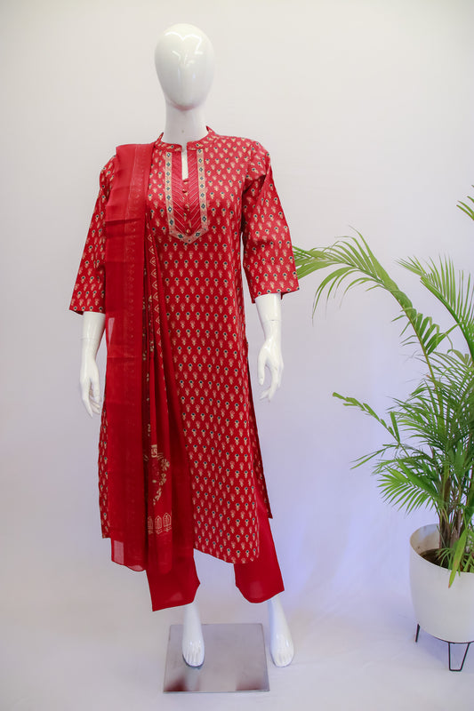 A red dupatta set with floral prints displayed on a mannequin, consisting of a kurta, pants, and a dupatta.