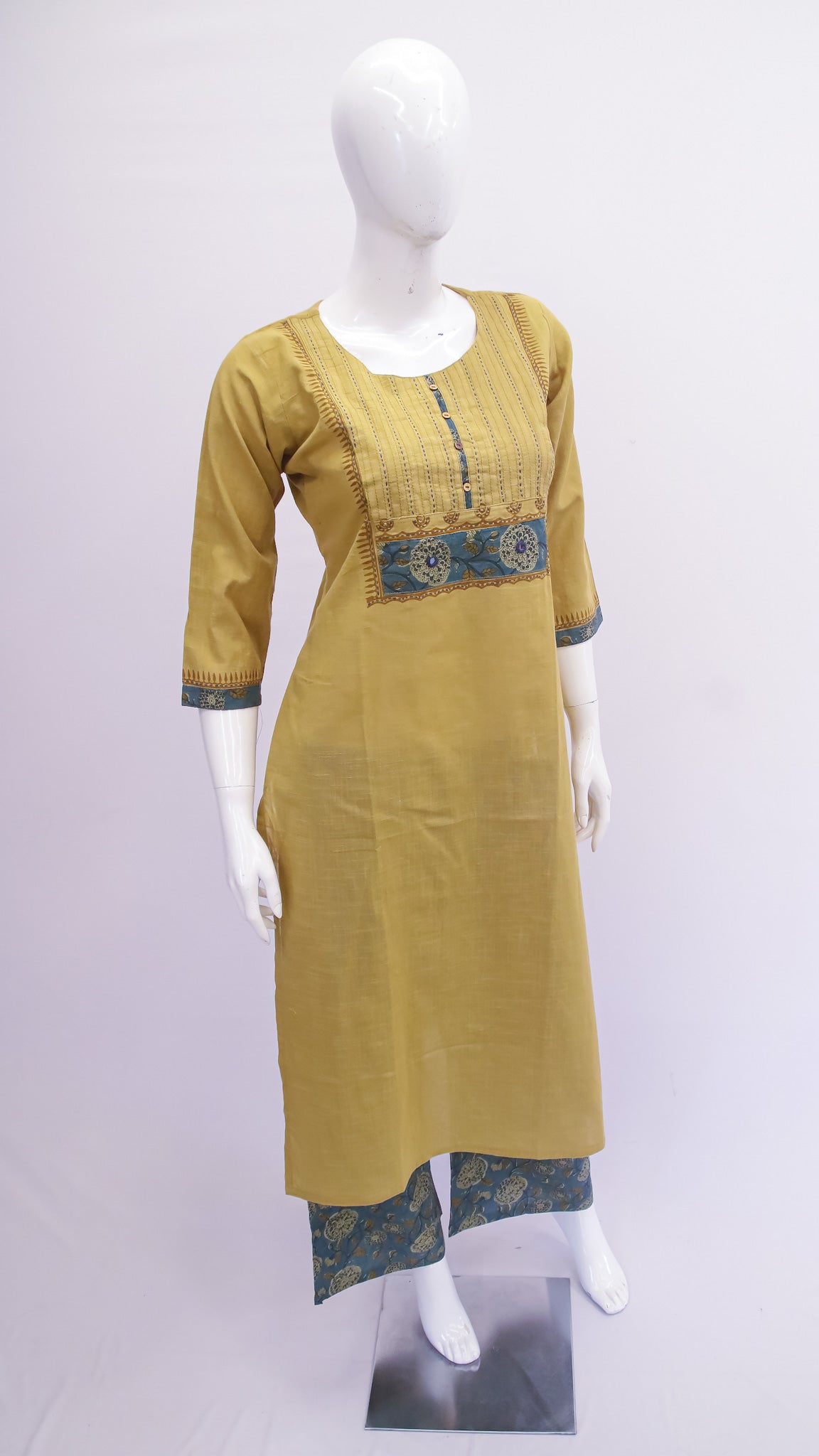 Mustard yellow kurta with green and blue patterns on a mannequin against a white background
