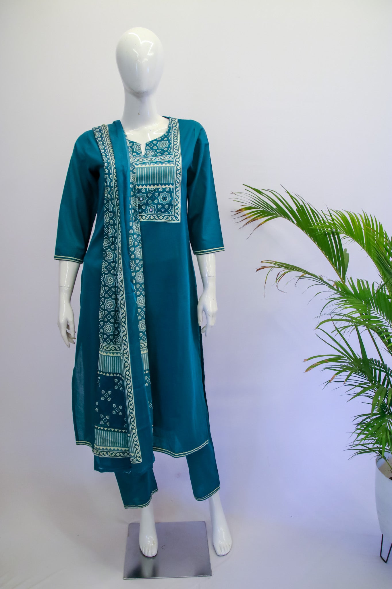 Teal embroidered dress on a mannequin with a white background