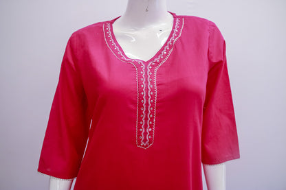 Red blouse with white embroidery on a mannequin against a gray background