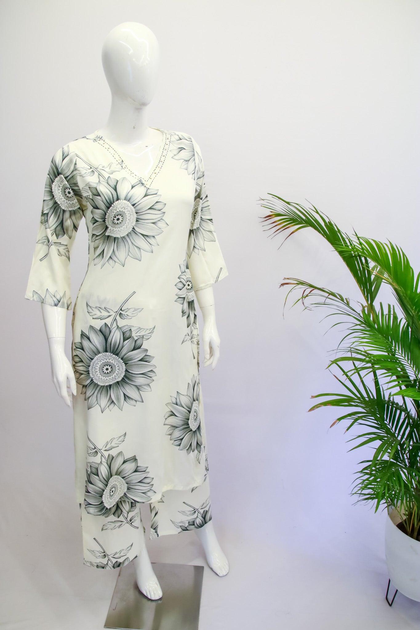White dress with black floral patterns on a mannequin against a white background