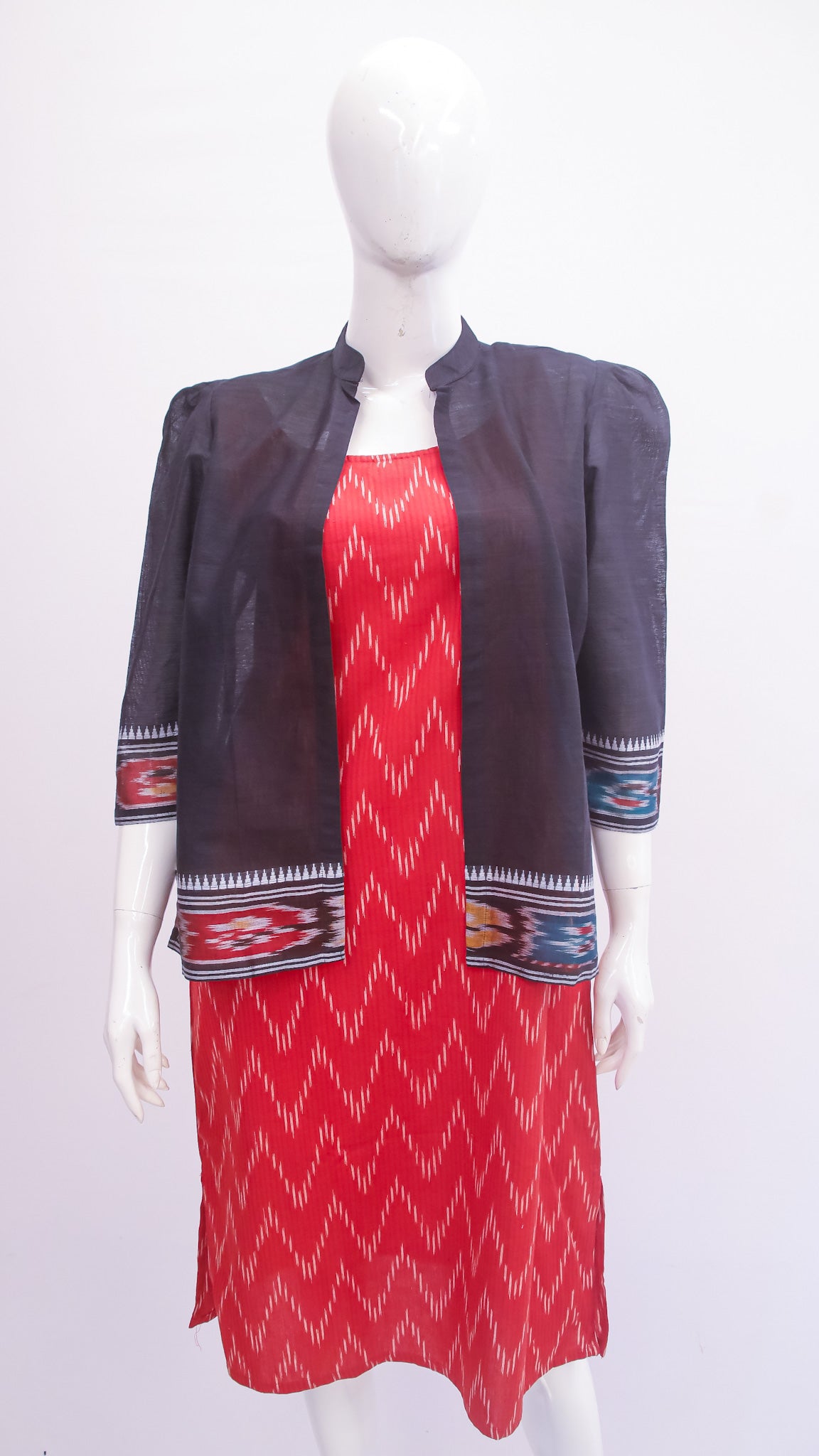 Mannequin wearing a red dress with patterned jacket on a white background