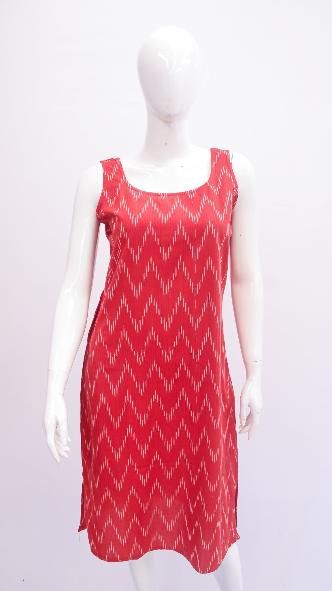 Red sleeveless dress with white pattern on a mannequin against a white background