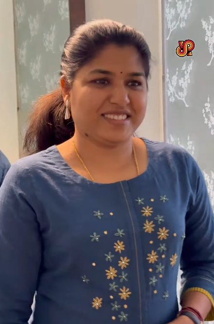 Woman wearing a blue embroidered top in an indoor setting