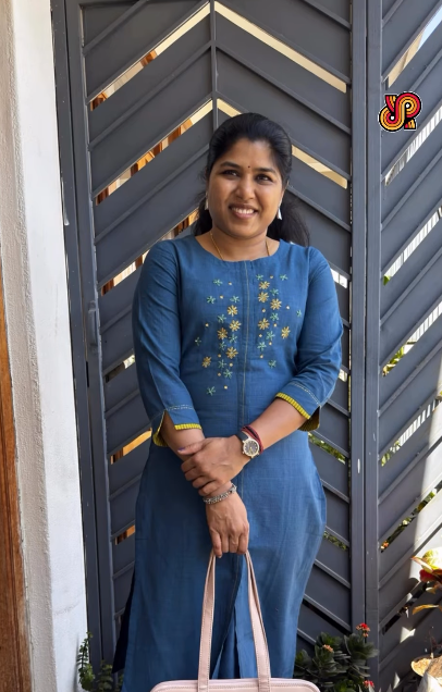 Woman in a blue dress standing in front of a dark gray door with decorative patterns.