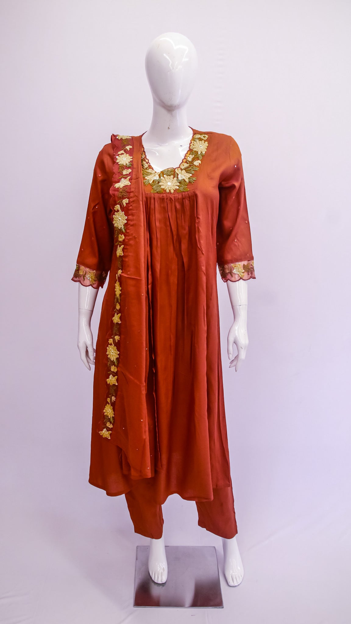 Red dress with gold embroidery on a mannequin against a white background