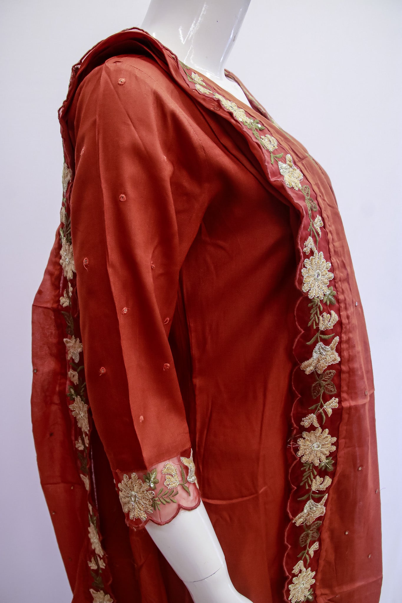 Red traditional outfit with gold embroidery on a mannequin against a white background