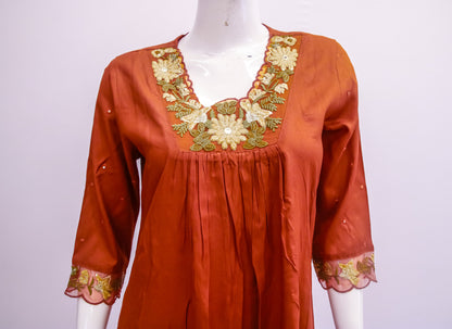Orange dress with floral embroidery on a mannequin against a white background