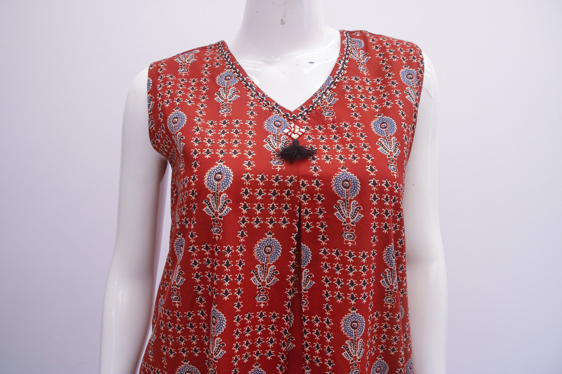 Red patterned sleeveless top on a mannequin against a white background